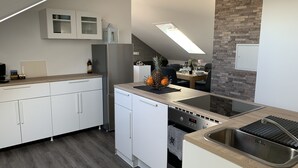 Ett modernt kök med vita skåp, en inbyggd ugn och en diskho i rostfritt stål.