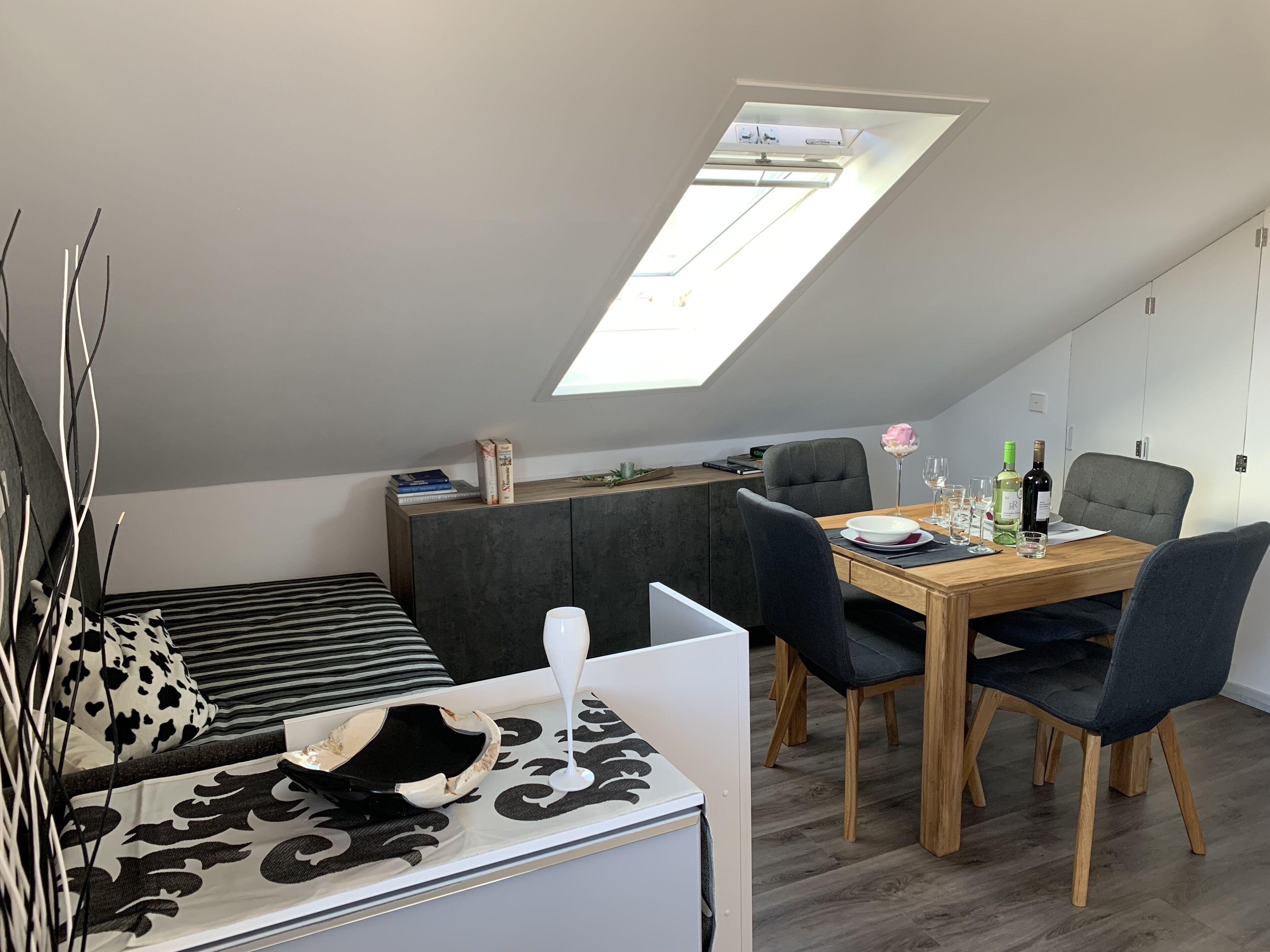 Ein modernes Loft-Schlafzimmer mit Dachfenster, Essbereich und einer gemütlichen Sitzecke.