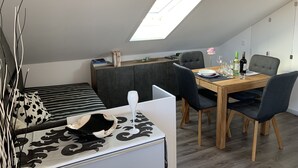 Ett modernt loftrum med ett takfönster, en matplats och en mysig sittgrupp.