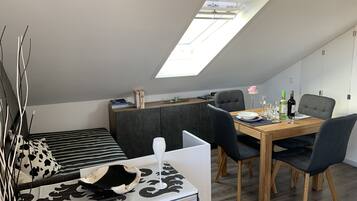 Ein modernes Loft-Schlafzimmer mit Dachfenster, Essbereich und einer gemütlichen Sitzecke.