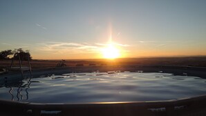 Cielo despejado con el sol poniéndose sobre una masa de agua, que refleja el cielo.
