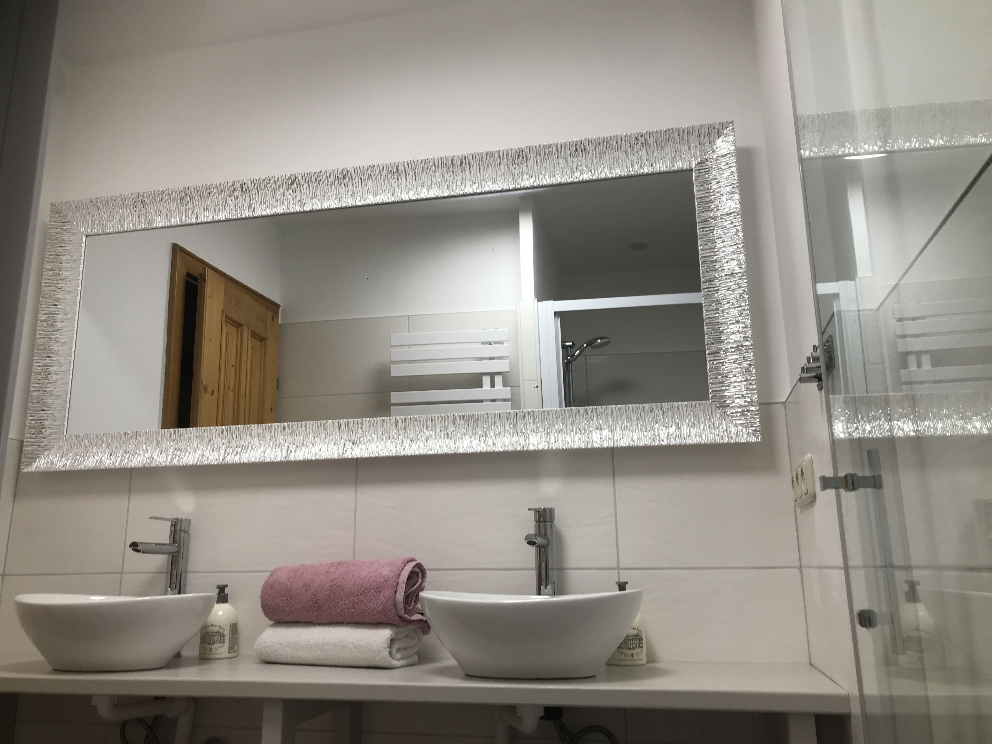 A bathroom with two sinks, a mirror, and a shower.