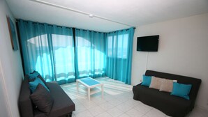 Ein Wohnzimmer mit einer Couch, einem Couchtisch und einem an der Wand befestigten Fernseher.