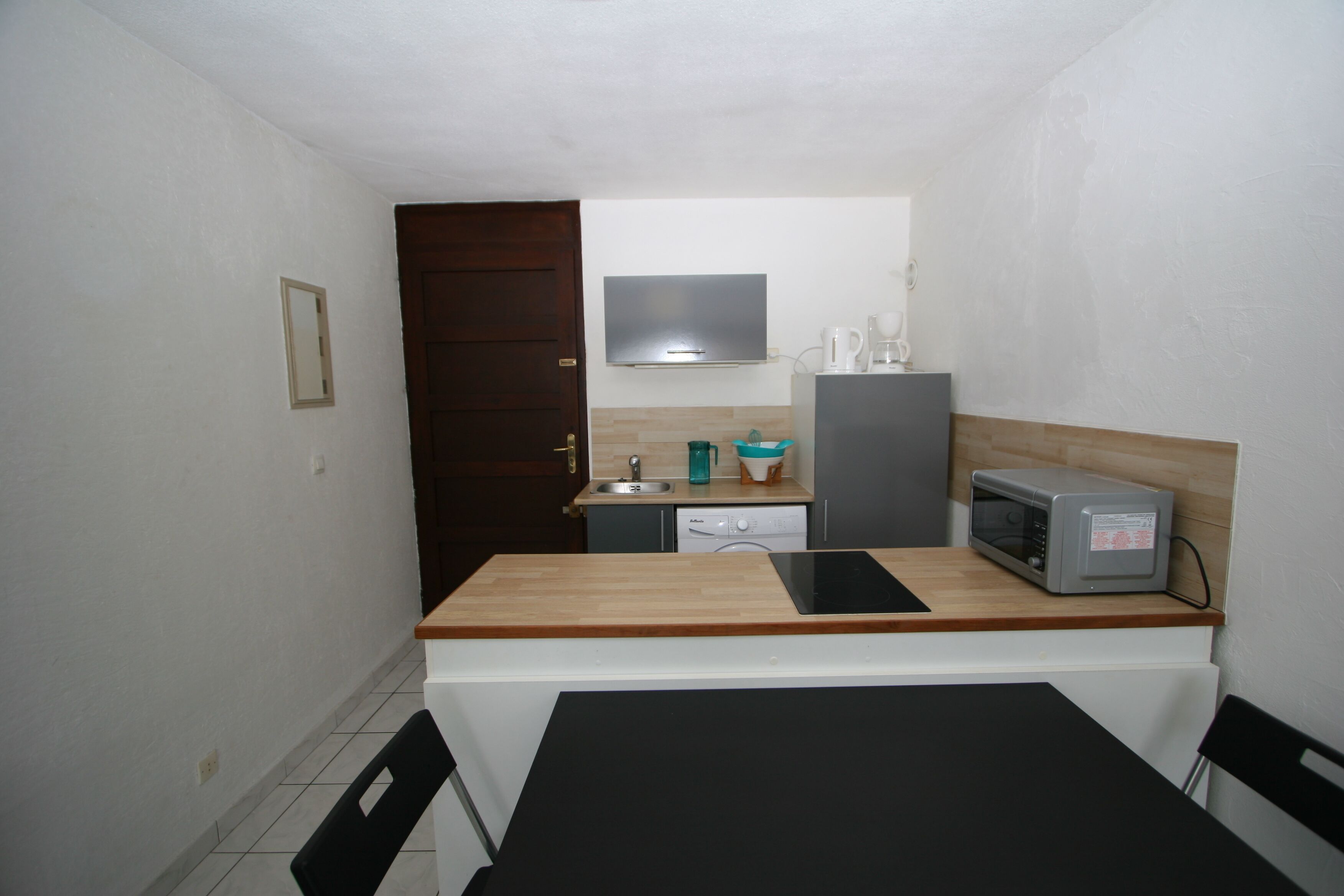 A small kitchen with a wooden countertop, a microwave, a dishwasher, and a sink.