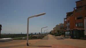 Ein gepflasterter Weg mit Straßenlaternen, ein Restaurant namens „Le Grand Place“ und ein Gebäude mit Balkonen und Fenstern.