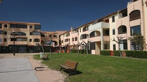 Ein Innenhof mit einer Bank, einem Weg und einem Gebäude mit mehreren Balkonen und Rundbogenfenstern.
