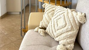 A modern interior with a spiral staircase, a kitchen area, and a cozy seating area with a textured throw pillow.