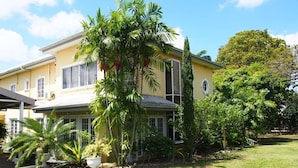 Une maison à deux étages avec une façade jaune, de grandes fenêtres et une pelouse bien entretenue.