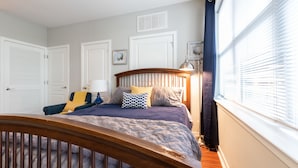 Une chambre à coucher avec un lit en bois, une tête de lit et une fenêtre équipée de stores.