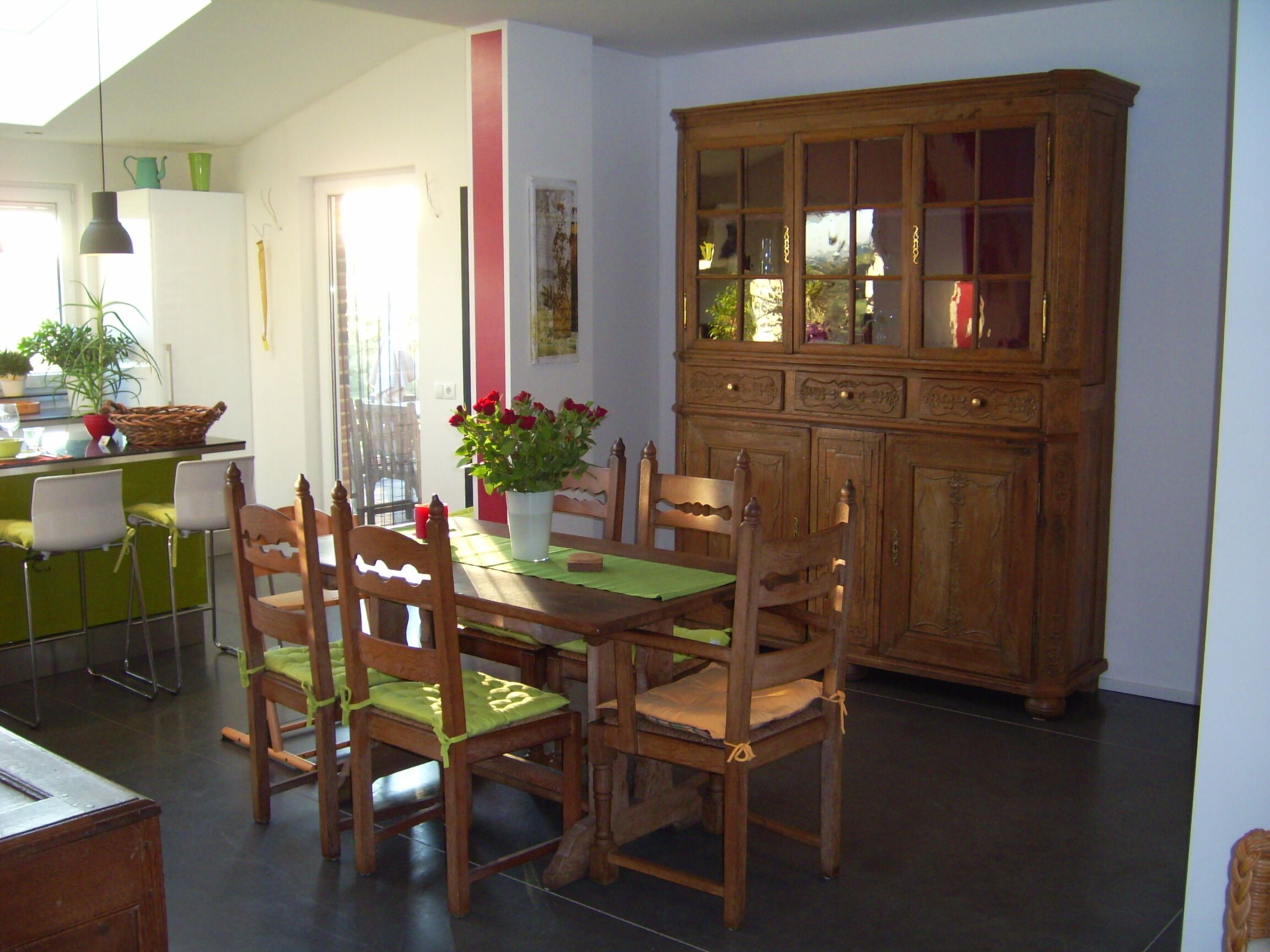 Zona pranzo con tavolo in legno, quattro sedie, un armadio e una pianta in vaso.