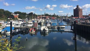 Ein Yachthafen mit vertäuten Booten, einem Leuchtturm und Gebäuden im Hintergrund.