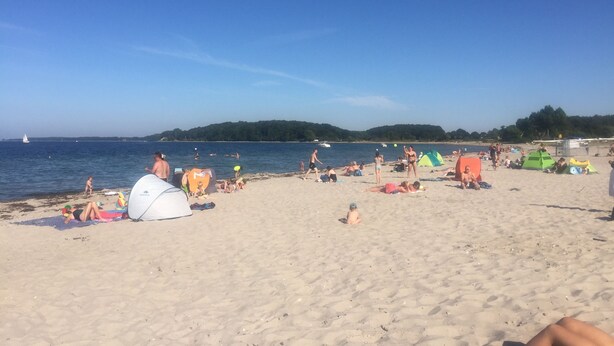 Ein Strand mit Zelten und entspannten Menschen.