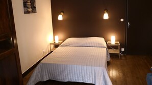 Un dormitorio con una cama, dos mesitas de noche y dos lámparas de pared.