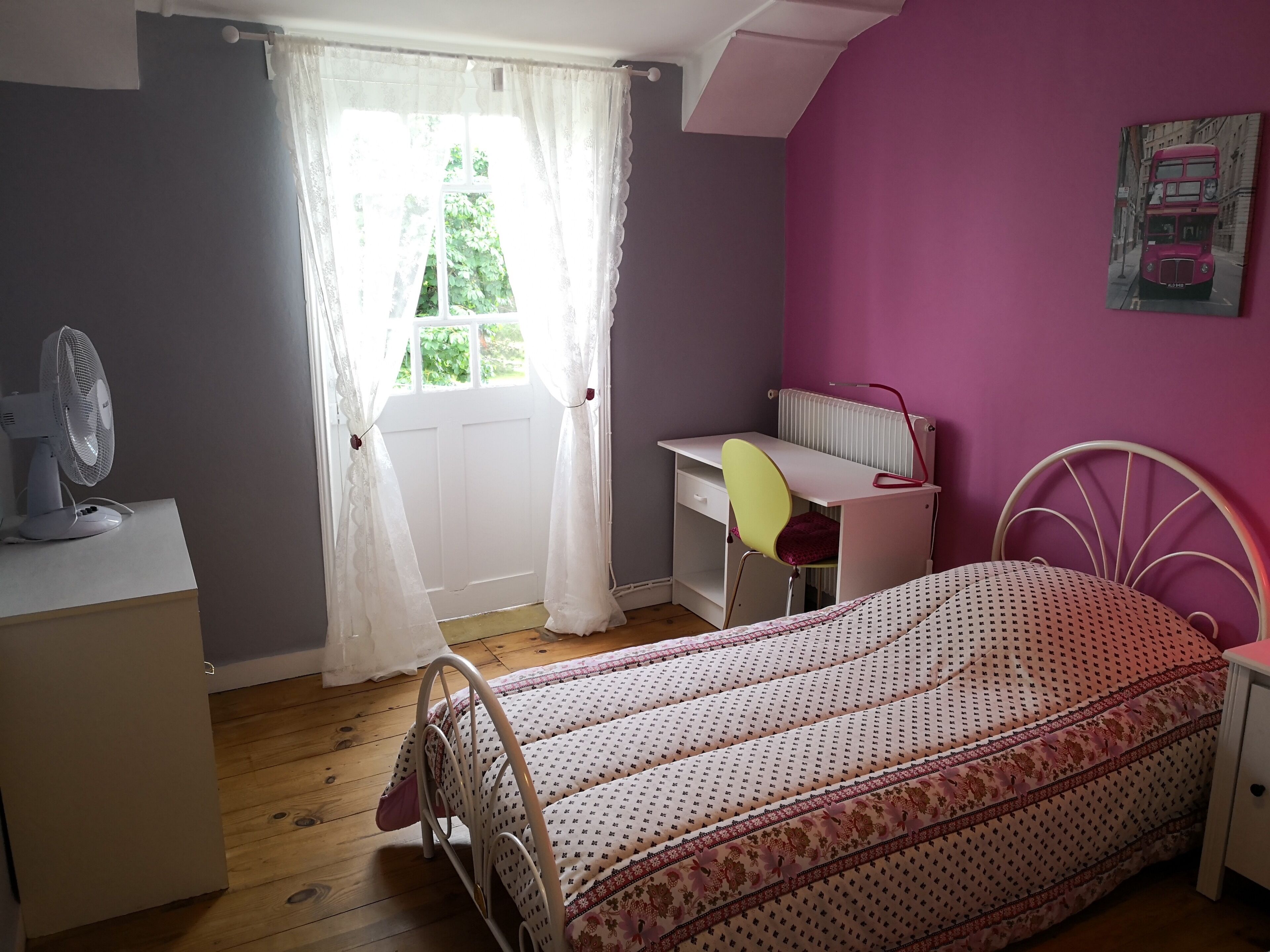 A bedroom with a bed, a desk, and a chair.