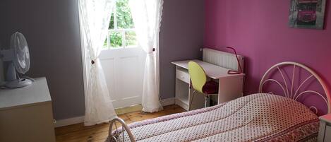 A bedroom with a bed, a desk, and a chair.