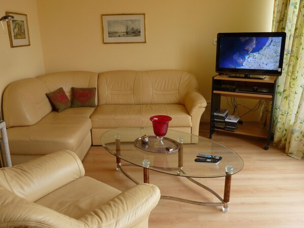 A living room with a beige sofa, a glass coffee table, and a television on a stand. - New apartment in centre of Heviz, only 50 m to thermal lake (Heviz)
