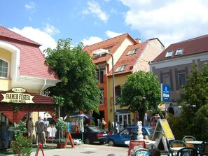 A street scene with a shop named "FARMER FESZER JEANS MODE" and a K&H bank sign. - New apartment in centre of Heviz, only 50 m to thermal lake (Heviz)