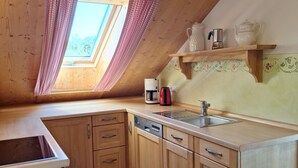 A kitchen with wooden cabinets, a sink, and a window with curtains. - Heissbauer Vacation Rental "Rosentraum" with Mountain Views and Two Bedrooms (Wackersberg)