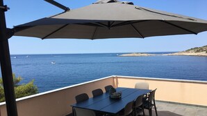 A terrace with a table and chairs, overlooking a coastal view with boats and a rocky island. - Directly by the sea, A4 - Penthouse apartment, 180m², 8 pers. (Razanj)