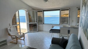 A modern living room with a sofa, a dining table, and a chair. Large windows offer a view of the sea. - Directly by the sea, A4 - Penthouse apartment, 180m², 8 pers. (Razanj)