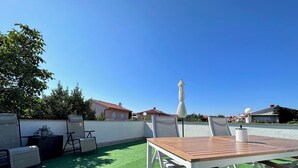 A patio with a table and chairs, a potted plant, and a view of houses in the background. - Apartment Sonja with a great terrace, near the beach, close to center (Krk)