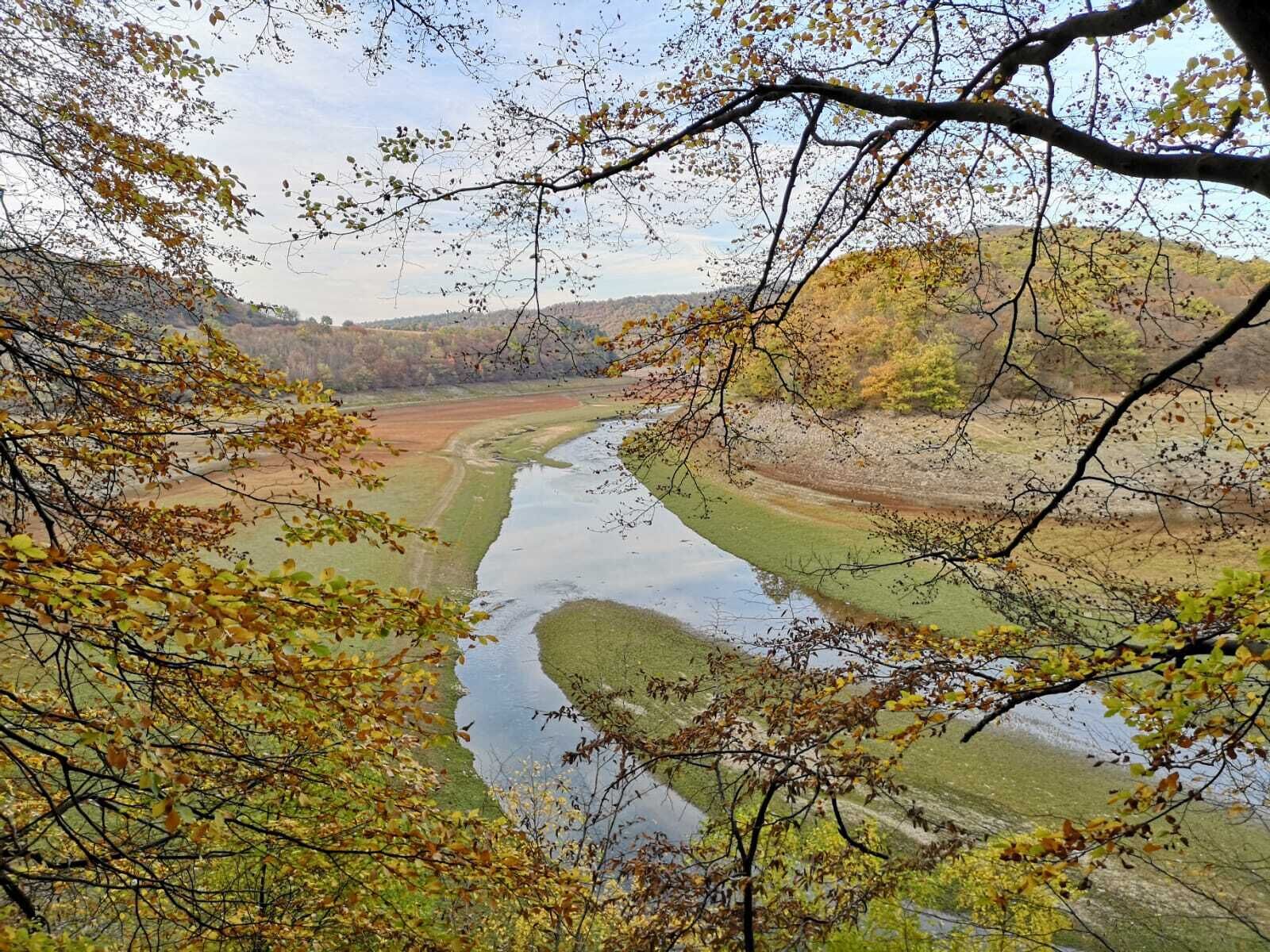 A river flowing through a valley with autumn foliage.