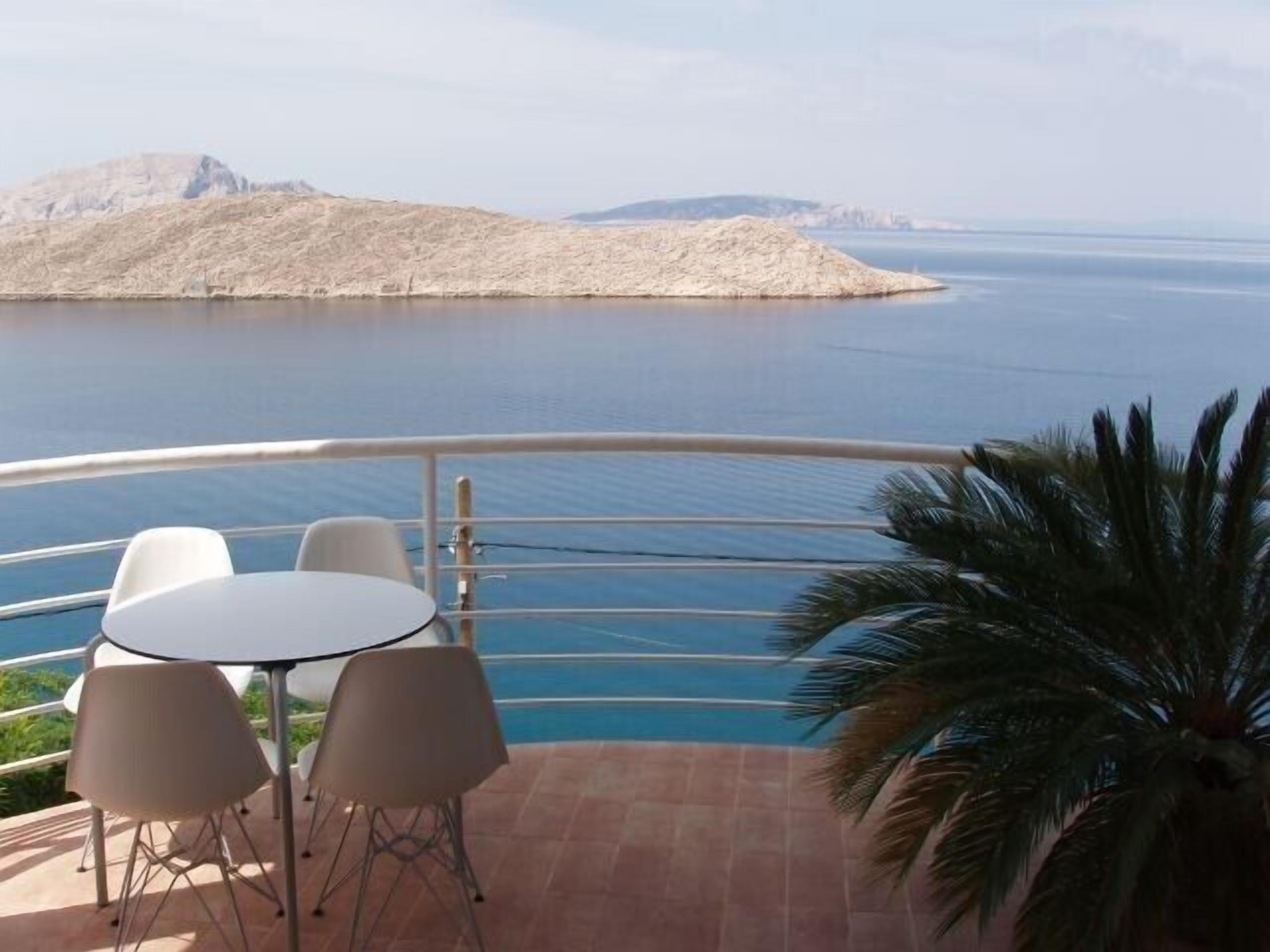 Una terraza con mesa y sillas con vistas a un cuerpo de agua y una montaña distante.