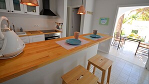 Een moderne keuken met houten aanrechtbladen, roestvrijstalen apparatuur en hanglampen.