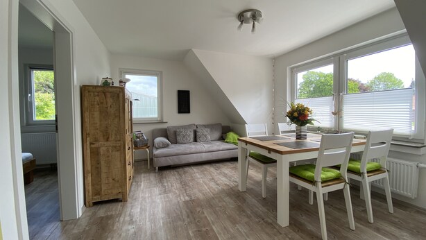 Een moderne loft met een eethoek, een bank en een houten kast.
