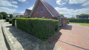 Een woongebouw met een rode bakstenen gevel, een pannendak en een verharde oprit.
