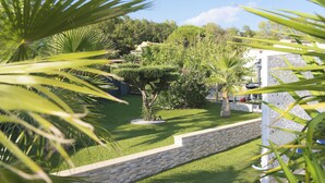 A well-maintained garden with a stone wall, various shrubs, and a white fence. - Apartment with pool on the Cote Azur (Bagnols en foret)