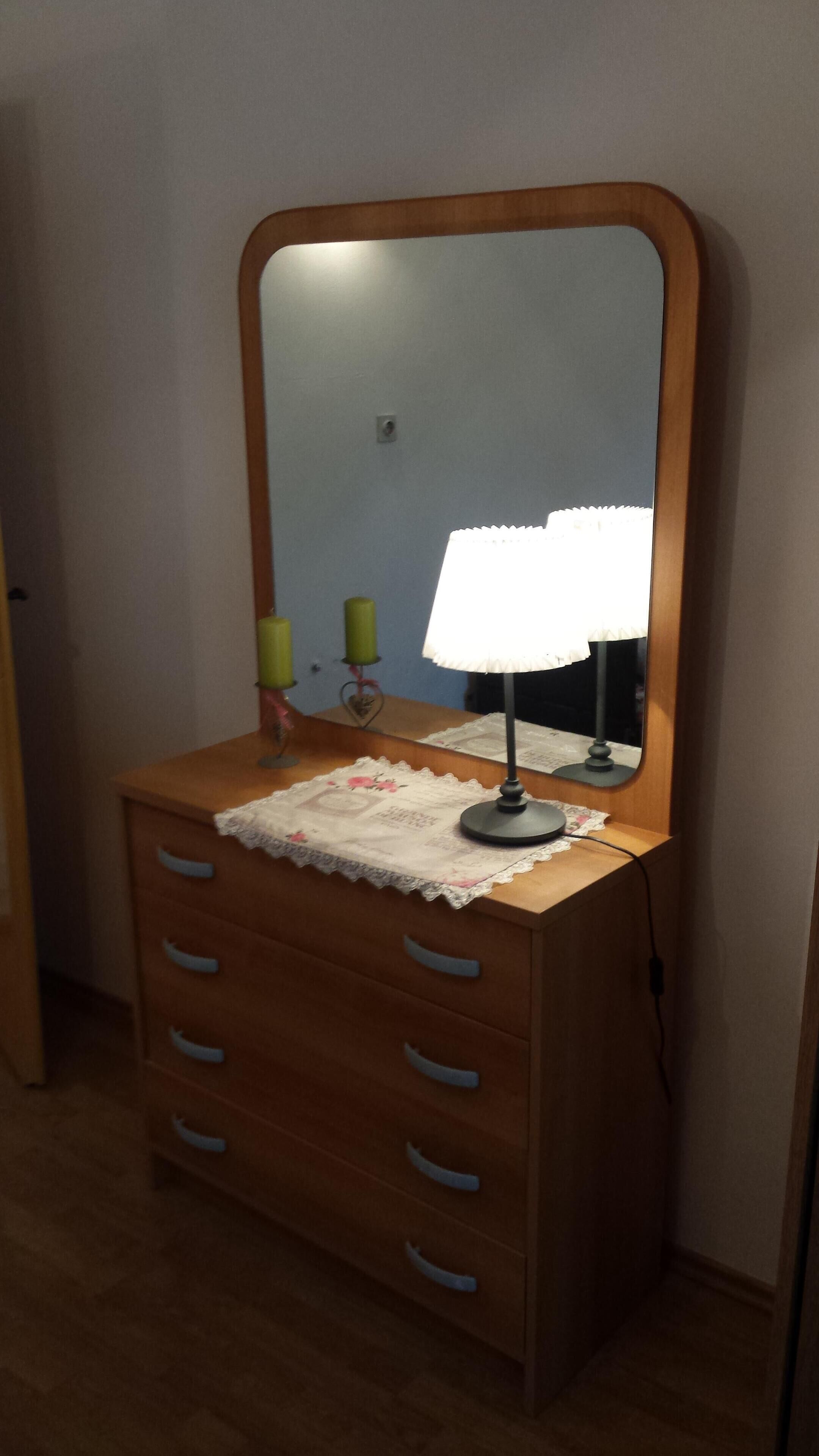 A wooden dresser with a mirror and a lamp.
