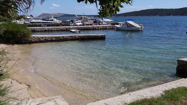 A marina with boats docked, clear water, and a stone wall. - A romantic Mediterranean apartment (Barbat na Rabu)