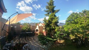 Ein Patio mit Steinboden, Gartenmöbeln und einem Kamin.