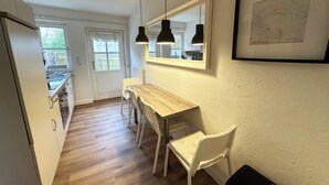 Una cocina moderna con una mesa de comedor de madera, sillas blancas, luces colgantes y un mapa enmarcado en la pared.