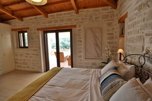 Une chambre à coucher avec un lit, une table de chevet, une lampe et une vue sur l’extérieur.