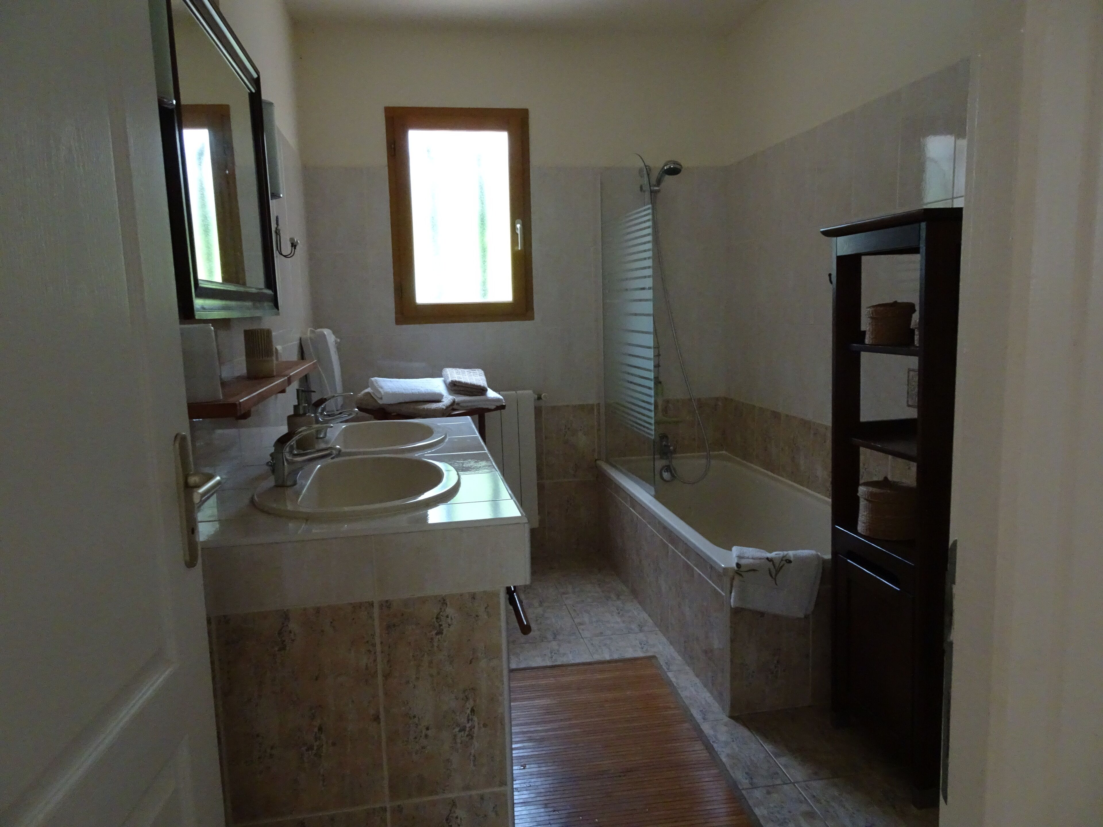 A bathroom with two sinks, a bathtub, a shower, and a window.