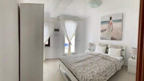Una camera da letto con un letto, un comodino, un quadro e una finestra con tende.