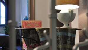 Une pièce avec une lampe de table, un tableau encadré et une chaise.
