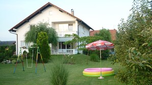 Une maison avec un porche à l’avant, une balançoire et une piscine gonflable.