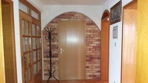 Un couloir avec une porte en bois, un porte-manteau et un mur en briques.