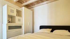 Une chambre à coucher avec un lit, une armoire blanche et un plafond en bois.