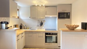 Une cuisine moderne avec des armoires blanches, un four encastré, un four à micro-ondes et un plan de travail en bois.