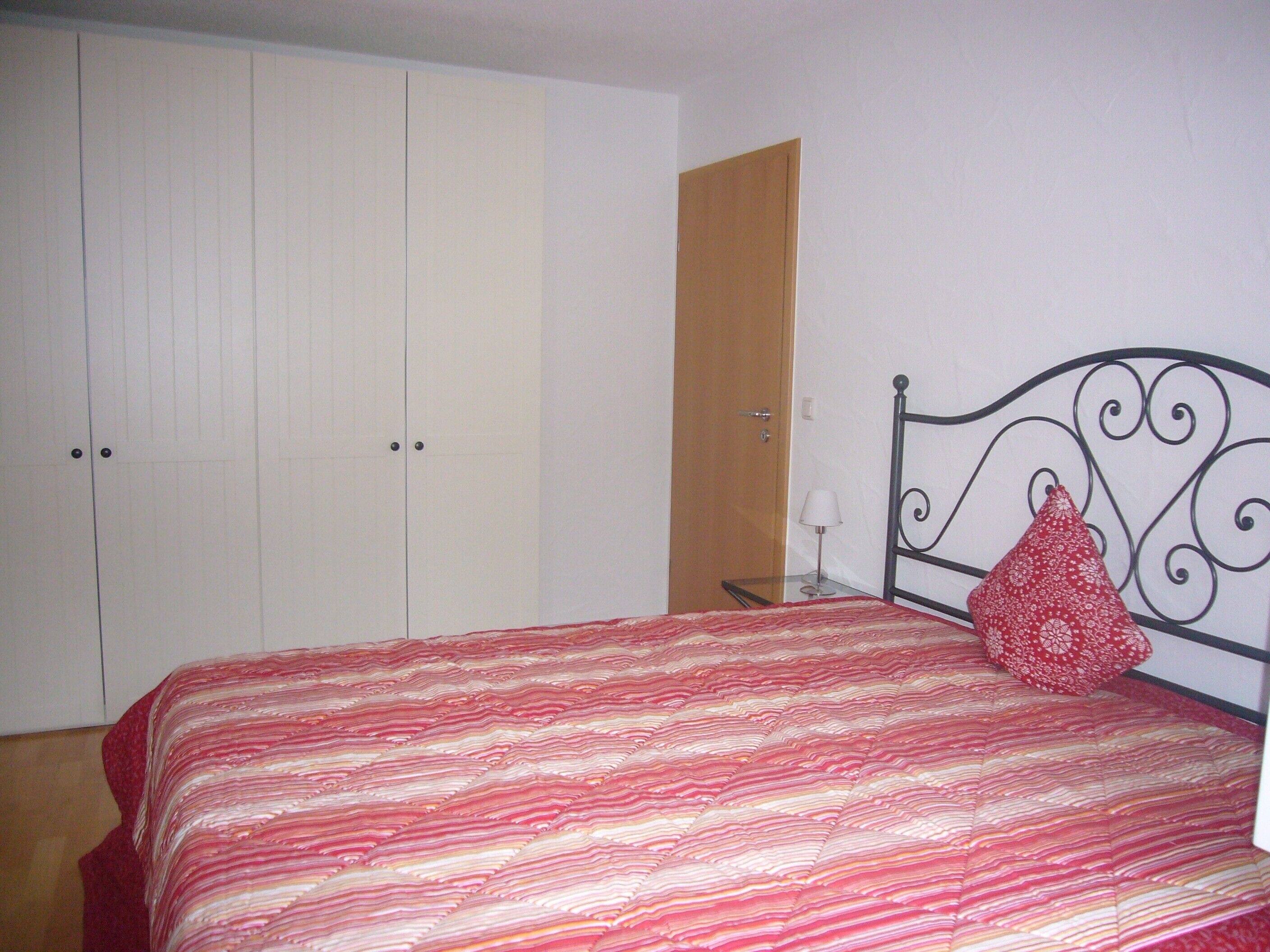 Ein Schlafzimmer mit einem Bett, einem Kleiderschrank und einem Nachttisch.