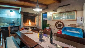 Ein rustikaler Essbereich mit Kamin aus Ziegeln, Holzbänken und einem für zwei Personen gedecktem Tisch mit Weingläsern.