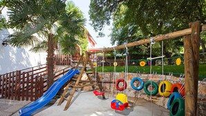 Ein Spielplatz mit Rutsche, Schaukeln und Reifen.