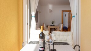 A balcony with a table, a bottle of wine, and two wine glasses.