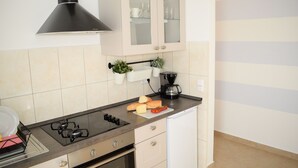 A kitchen with a gas stove, a coffee maker, and a cabinet with glass doors. - SPECIAL OFFER! Studio APARTMENT with BALCONY (Kaštel Stari)