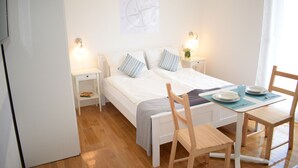 A bedroom with a bed, bedside tables, a desk with chairs, and a wall-mounted light fixture. - SPECIAL OFFER! Studio APARTMENT with BALCONY (Kaštel Stari)