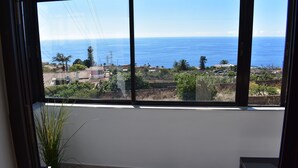 Ein Zimmer mit großem Fenster und Blick auf die Küste, inklusive Meer und Wohngebiet.